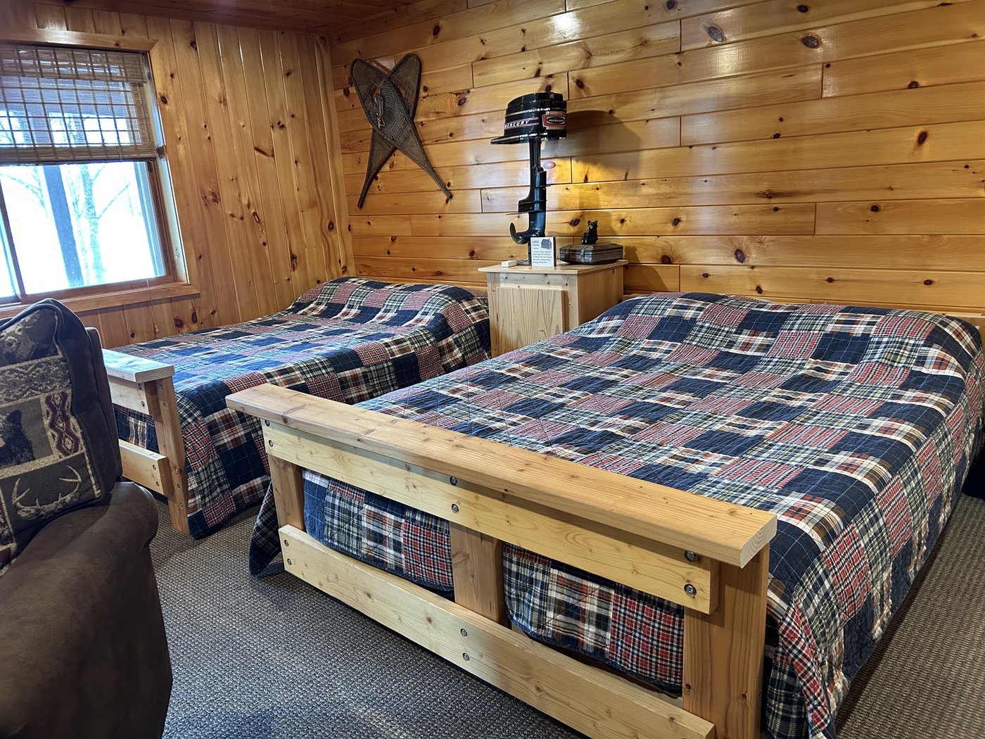 Lower-level room with two queen beds with plaid quilts and log frames